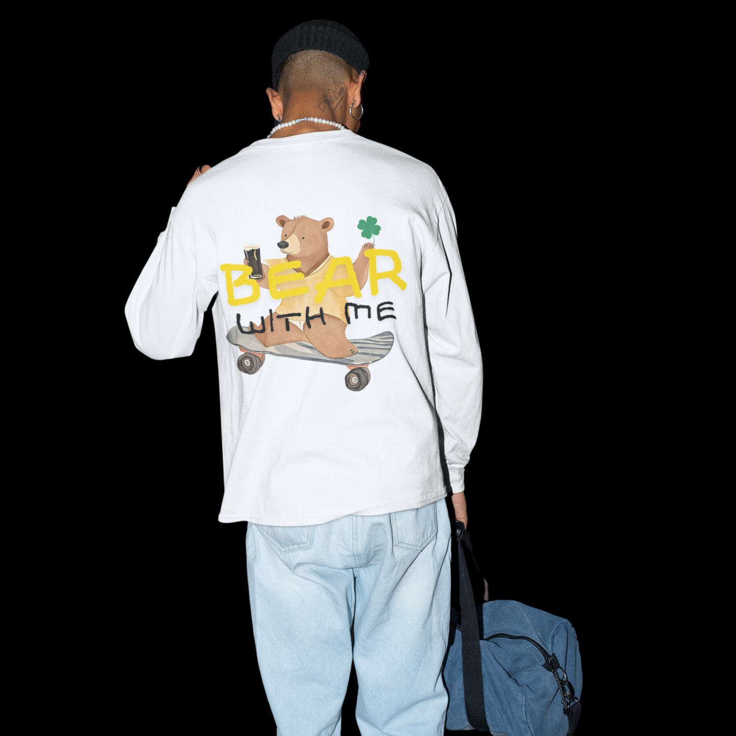 Long sleeve t-shirt featuring a playful graphic on the back of a bear riding a skateboard while holding an Irish beer and a shamrock. The text 'Bear With Me' is displayed above the bear. 